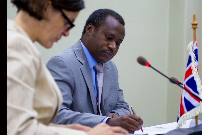 Ndagijimana (R) and Beaufils sign the deal in Kigali yesterday.  (Timothy Kisambira.)