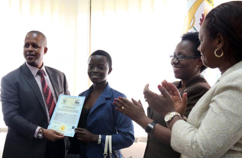 Gasana (left) hands over a certificate to Josiane Nyiramana, from IPRC South, who topped the 2013 national exams, as heads of technical and vocational schools cheer yesterday. (John Mbanda)