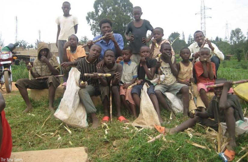 The Roots Foundation director, Patrick Kiruhura (wearing a blue shirt), enjoys a sugarcane with street children. (Hassan Mutuhe)