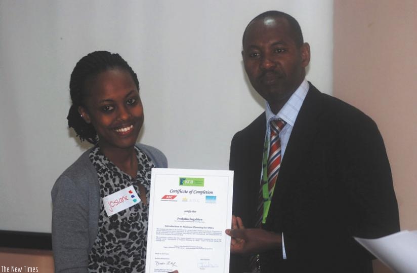 A participant receives a certificate from Nkusi after the one-day training in financial management skills in Kigali. (Peterson Tumwebaze)