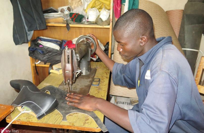 Alphonse Karangwa, a shoe maker, sews leather at Twitezimbere Cooperative in Kibeho, Nyamagabe. (E. Ntirenganya)