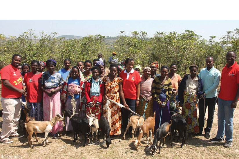 Mumararungu (middle, in kitenge attire) and Airtel staff pose with some of the beneficiaries and their goats. Mumararungu and Edna Darlene Gasana were rewarded for their contribution toward improving their communities.  