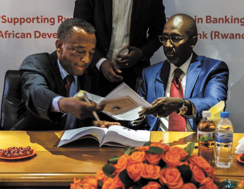 Karayenzi (right) and Makonnen exchange documents after signing the loan agreement yesterday. The funds target small businesses. (Timothy Kisambira)