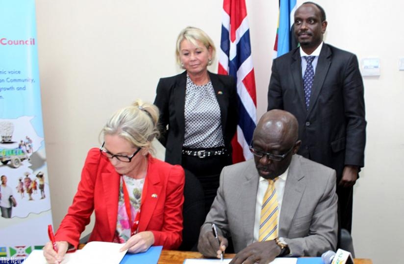Traaseth (L) and Karera sign the paperwork in a ceremony witnessed by Maeland, and Sezibera (standing right) in Arusha, Tanzania, yesterday. (Courtesy)