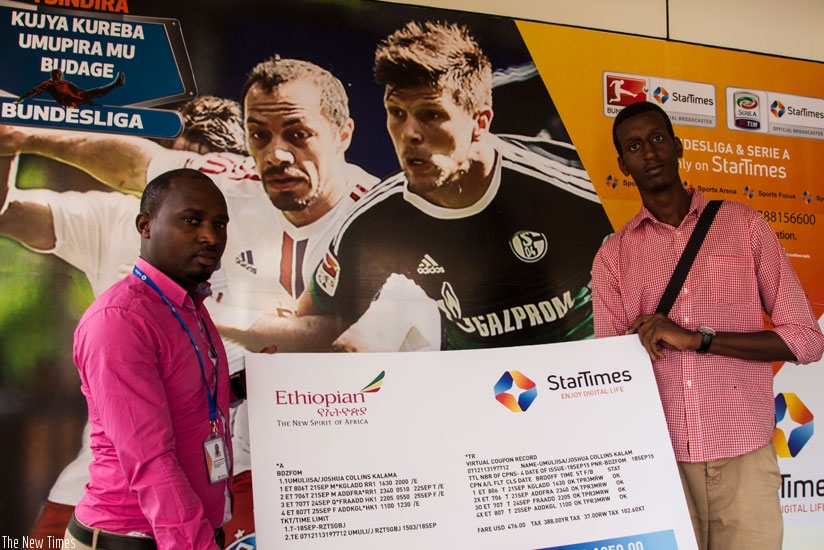 The New Times sports reporter, Joshua Collins Kalama (R), seen here receiving his air ticket from StarTimes Public Relations manager, Claude Nahimana, yesterday. (Faustin Niyigena)