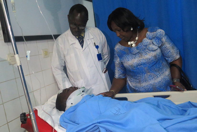 Minister Dr Binagwaho (R) and CHUK director-general Dr Theobald Hategekimana check on Etienne Nsanzimana, one of the two survivors of yesterday's road accident that killed 18 people on the spot in Rwamagana District. (Jean Mugabo)