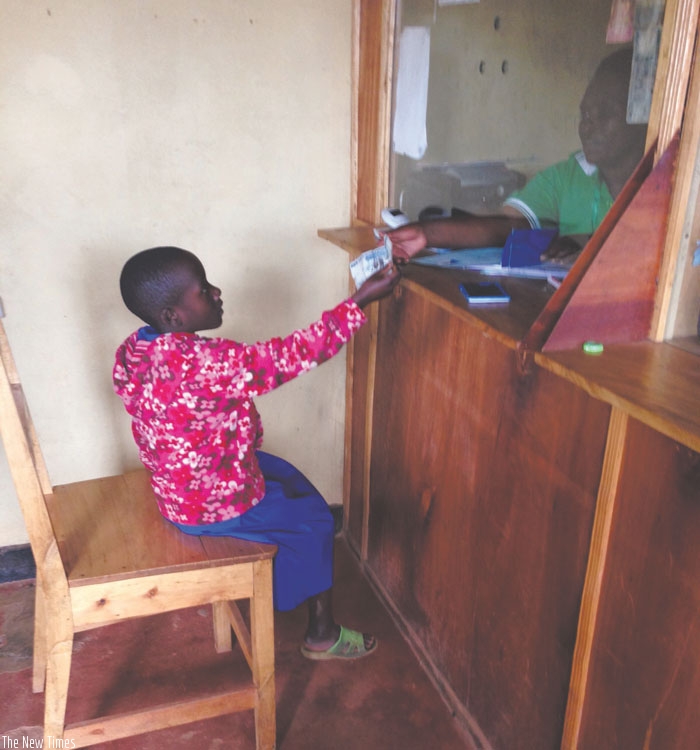 A cashier at a microfinance attends to a young saver. Mobilising savings is key for a country's growth.  (P. Tumwebaze)