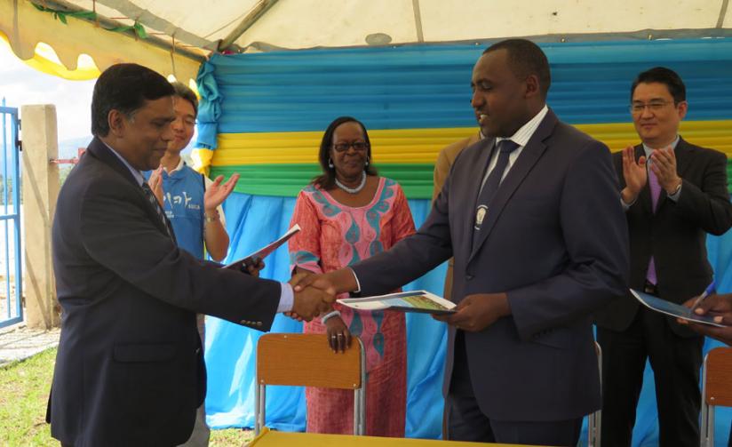Siddiqui (L) shakes hands with Nyamagabe District Mayor Philbert Mugisha, as Regine Iyamuremye, the Executive Secretary of the Unity Club, looks on, at the hand over ceremony of the development activities under the Saemaul Zero Hunger Communities project. (Emmanuel Ntirenganya)