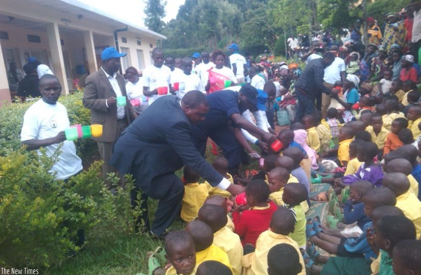 Zaraduhaye (L)  and other officials give milk to  children during the event. (Jean Fidele Ndungutse)