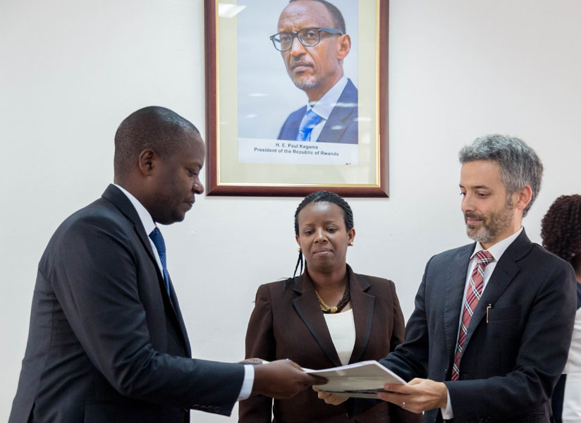 Emmanuel Kamanzi, the managing director of Energy Development Corporation Ltd (L), exchanges documents with Yariv Cohen, the director of Ignite Power Ltd, as State Minister for Energy, Water and Sanitation Germaine Kamayirese looks on. (Timothy Kisambira)