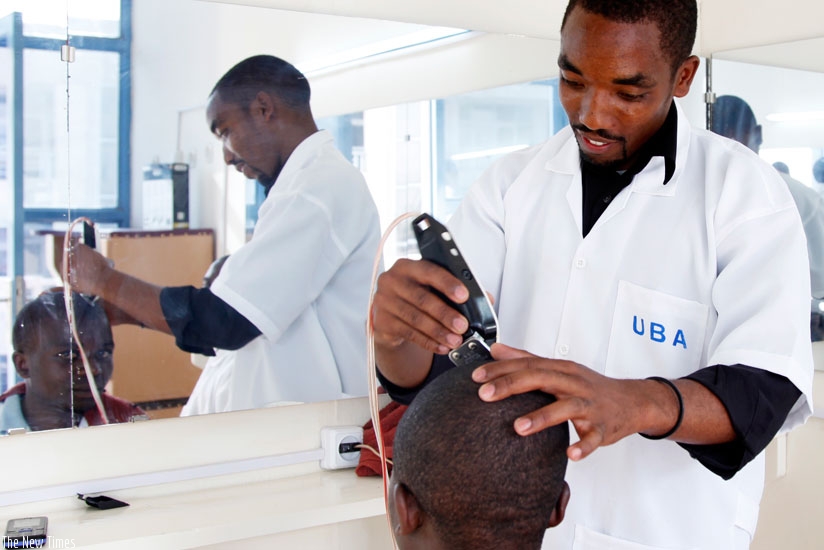 A barber shaves a client in Kimironko. (Timothy Kisambira)