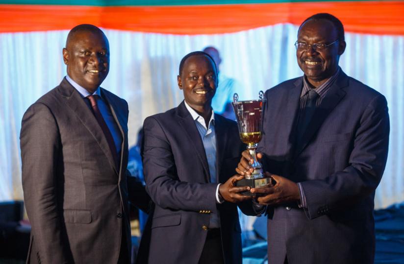 CIMERWA's Malidadi (C) receives the best exhibitor trophy from Kanimba (R) as Gasamagara looks on. (Courtesy)