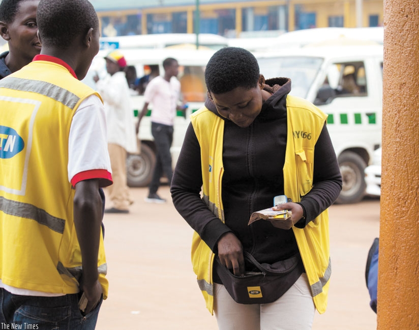 A mobile money vender transacts business  on a cell phone in downtown Kigali. (T. Kisambira)