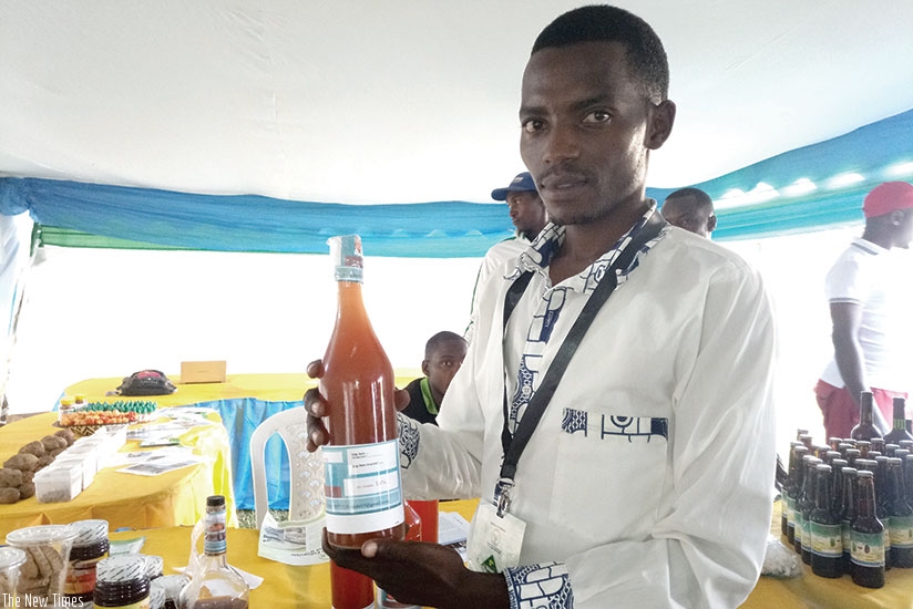 Ntezimana displays one of his products, the Iyiwacu Wine brand, which he makes from sweet potatoes. / Michel Nkurunziza.