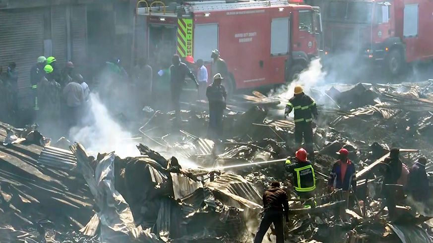 Fire fighters obscured by smoke as they damp down the charred debris after a fire swept through a marketplace in Nairobi, yesterday. Net photo.