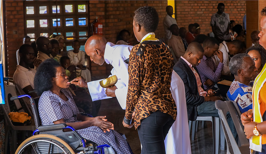 A person with disability receives a holy communion at Saint Michel Cathedral on Christmas Day.